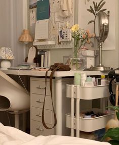 a white desk topped with lots of drawers under a mirror next to a lamp and flowers