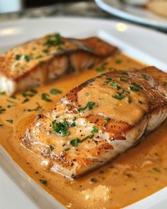 a piece of fish covered in sauce and garnished with parsley on a white plate