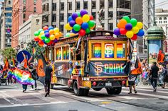 a trolley car with balloons on the back driving down a city street