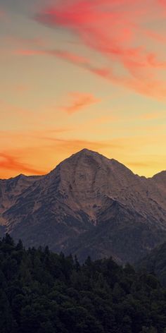 the mountains are covered in trees as the sun sets