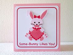 a card with a bunny holding a heart in it's paws, says some - bunny likes you