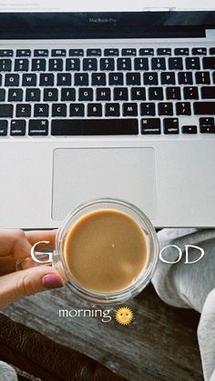 a person holding a cup of coffee in front of a laptop