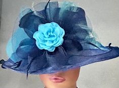 "The featured hat is a large, dressy, exotic  blue and teal hat. Organza and crinoline designs in navy blue along with a spray of teal feathers, multiple loops of teal crinoline and a beautiful teal colored flower. This exotic hat will be perfect for your Church Hat or  your favorite Audrey Hepburn look. This hat is also perfect for the Kentucky Derby ,a tea party, Wedding Party hat  and many other special  occasions.  Brim: 4\" Rise: 3.5\" Size:  Internal draw string allows one to adjust the si Chic Fitted Blue Hat, Chic Blue Fitted Hat, Fitted Blue Hat For Garden Party, Blue Hats For Church In Spring, Elegant Blue Mini Hat For Kentucky Derby, Elegant Blue Costume Hat For Evening, Blue Top Hat With Curved Brim For Formal Occasions, Blue Curved Brim Mini Hat For Races, Chic Blue Fascinator For Kentucky Derby