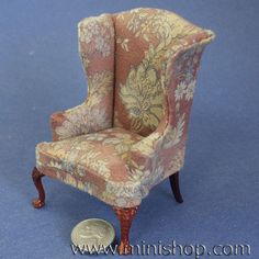 a miniature chair sitting on top of a blue floor next to a penny coin in front of it