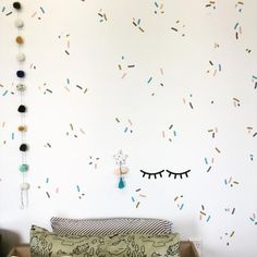 a bed sitting under a white wall with lots of sprinkles on it