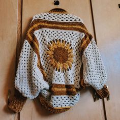 a crocheted sweater with a sunflower on the front and back, sitting on top of a wooden floor