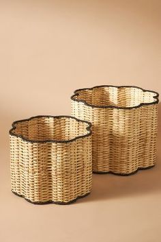 two wicker baskets with black rims sitting on a brown surface, one is empty