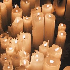 many lit candles are lined up in rows