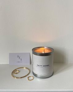 a candle and bracelet sitting on top of a white shelf next to a card that says,