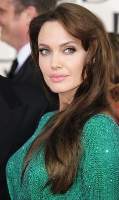 a woman with long brown hair wearing a green sweater and black suit on the red carpet