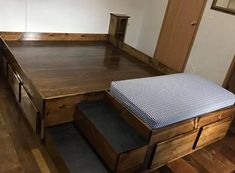 an empty room with a bed and two drawers on the bottom floor, in front of a mirror