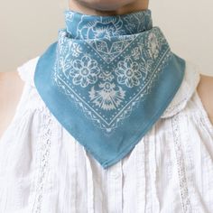 a woman wearing a blue bandana with white flowers on the front and back of her neck