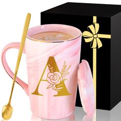 a pink marbled coffee mug next to a black gift box with a gold handle