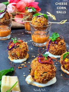 small appetizers with cheese, corn balls and vegetables on them sitting on a table