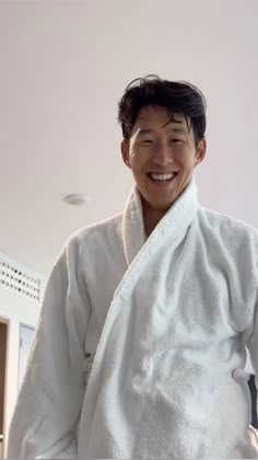 a man in a bathrobe is smiling for the camera