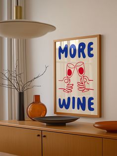 there is a sign that says more wine on the wall next to a plate and vase