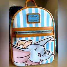 Like New Beautiful Loungefly Disney's Dumbo Striped Mini Backpack Is Brand New W/Tags. Features Include A Striped Pattern With A Die-Cut Dumbo, Main Zip Compartment, White Star Print On Tan Interior Lining, Front Zip Pocket With Bronze Tone Hardware, Enamel Brand Badge, Side Pockets, Brown Adjustable Straps. Measures Approx: 11.5" X 4.5" X 9". Loungefly Hello Kitty, Flying Elephant, Disney Loungefly, Faux Leather Backpack, Loungefly Bag, Disney Bag, Loungefly Disney, Backpack Bag, Metallic Logo