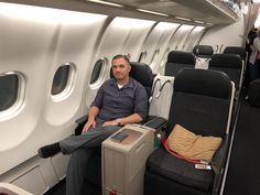 a man sitting on an airplane seat with his luggage