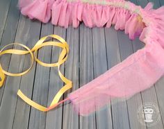 a pair of glasses and a yellow ribbon on a wooden floor with a pink tulle