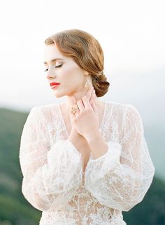 a woman in a white dress with her hands on her chest, looking off to the side