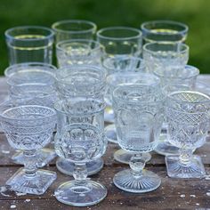 a bunch of glasses sitting on top of a wooden table next to eachother