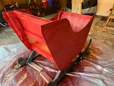 a red wagon sitting on top of a piece of plastic covered in wax and paint