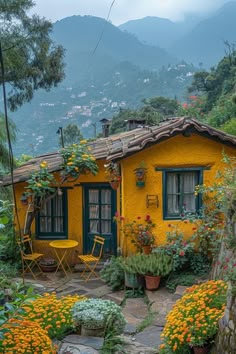 a yellow house surrounded by flowers and greenery