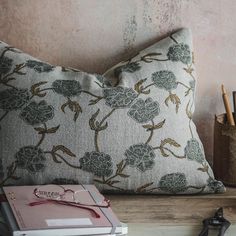 a pair of scissors and a notebook on a table next to a pillow with flowers