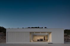 a person standing in the doorway of a white building at night with an open door