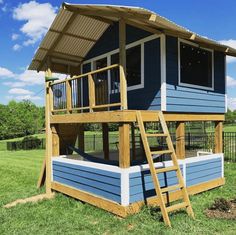 a blue and white house sitting on top of a lush green field