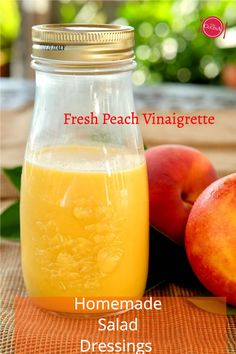 a glass jar filled with liquid next to two peaches