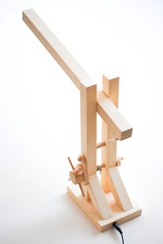 a small wooden machine that is sitting on a white surface with wires attached to it