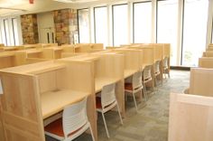 rows of desks and chairs in an empty room with large windows on both sides