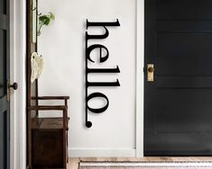 there is a black door with the word hello on it and a chair next to it