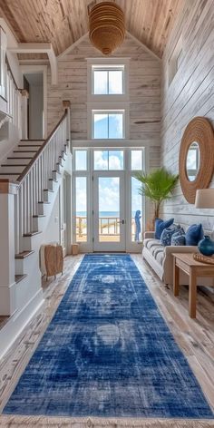 a large blue rug in the middle of a living room with stairs and wooden walls