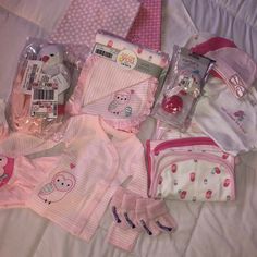 baby girl clothes and accessories laid out on a bed