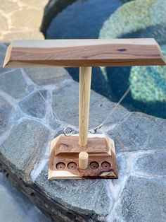 a wooden table lamp sitting on top of a rock next to a pool