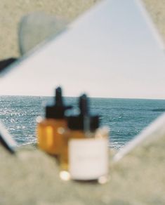 the reflection of a person in a mirror is seen on the beach near the ocean