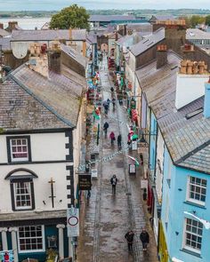 people are walking down the street in an old european town with blue buildings and cobblestone streets