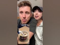 a man and woman sitting at a table with food in a bowl on the table