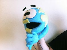 a person holding a blue stuffed animal in front of a white wall with black eyes