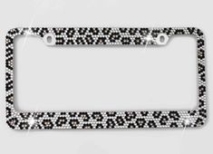 a black and white leopard print license plate frame with diamonds on the bottom, in front of a gray background