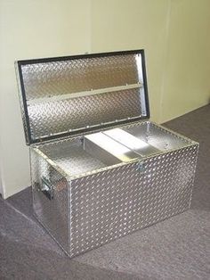 an open metal box sitting on the floor in front of a carpeted flooring area