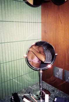 a woman's reflection in a mirror on a bathroom counter with other items nearby