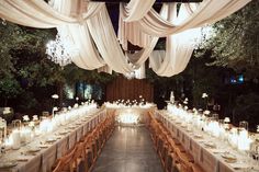 a long table is set up with white linens and candles