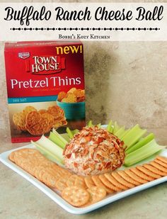 a plate with crackers, celery and cheese ball on it next to a box of town house pretzel thins