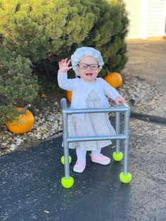 an older woman in glasses and a white dress is sitting on a small cart with green wheels