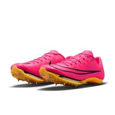 a pair of pink and yellow shoes with spikes on the soles, against a white background