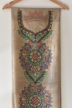 an embroidered wall hanging on a wooden hanger