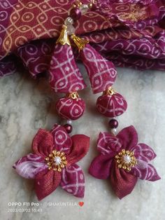 two pink and white flowers with gold accents on a purple fabric scarf or shawl